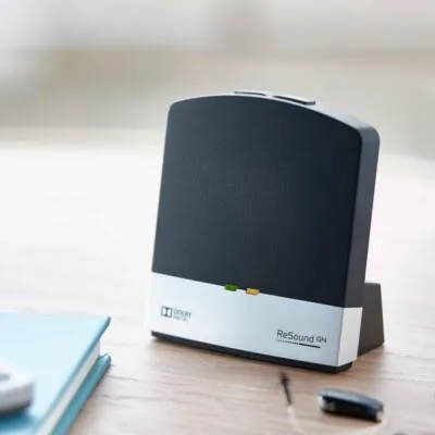 The GN ReSound TV Streamer 2 sitting on a table beside a television