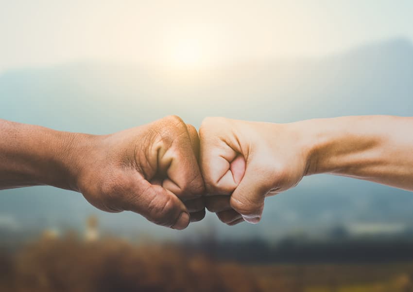 Two people bumping fists, representing commitment to the process