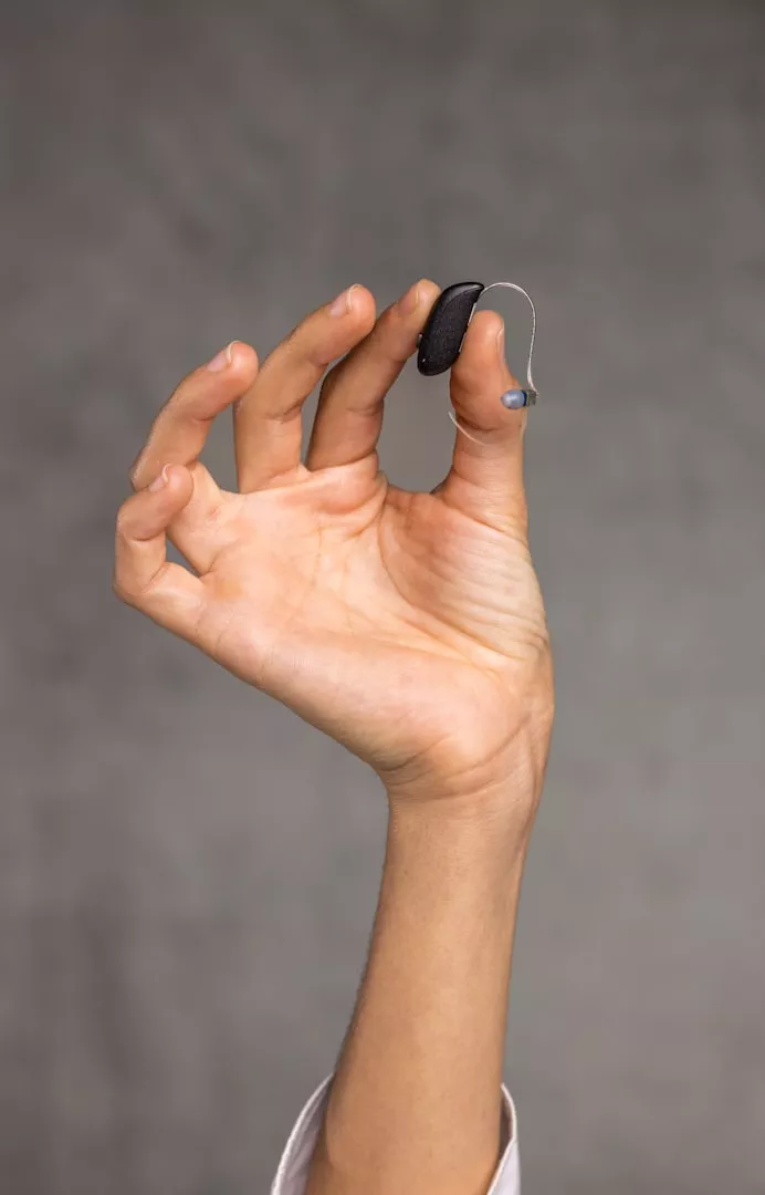A hearing aid held between finger and thumb