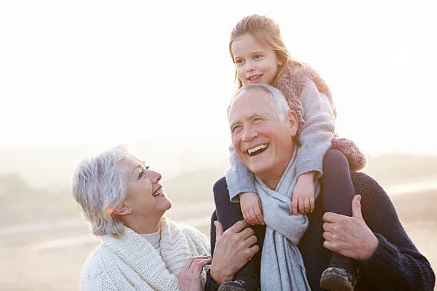 Grandparents at the beach with their granddaughter on his shoulders
