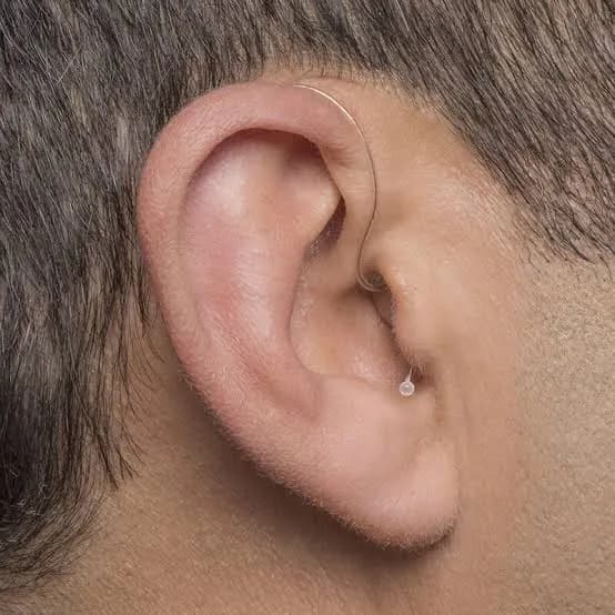 A receiver-in-canal hearing aid worn behind the ear, with a thin wire running into the ear canal